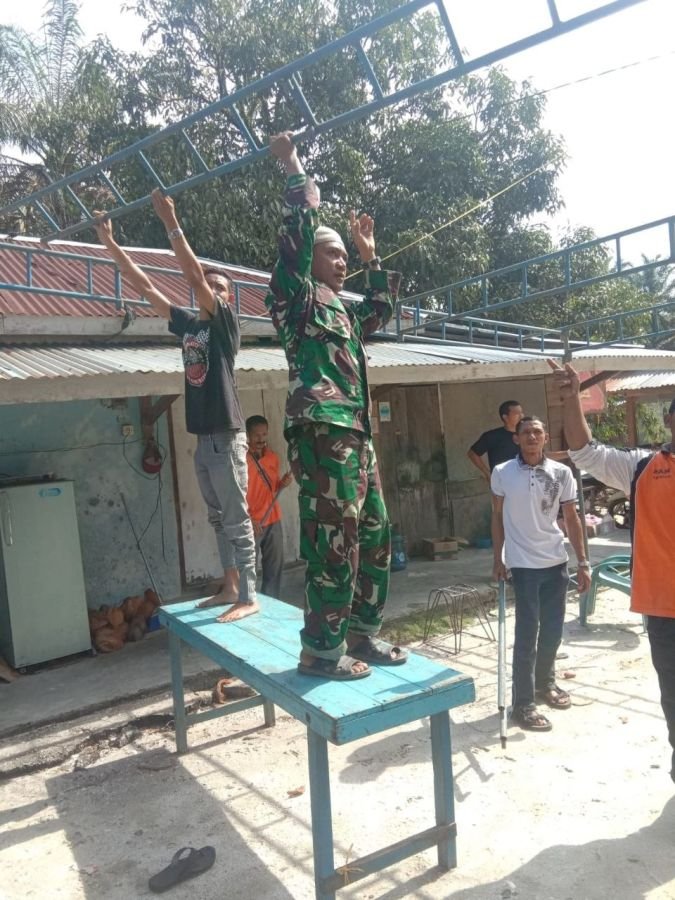 Babinsa Koramil 09/Singingi Sertu M. Afrianto Bantu Warga Dirikan Tenda Duka di Pasir Emas