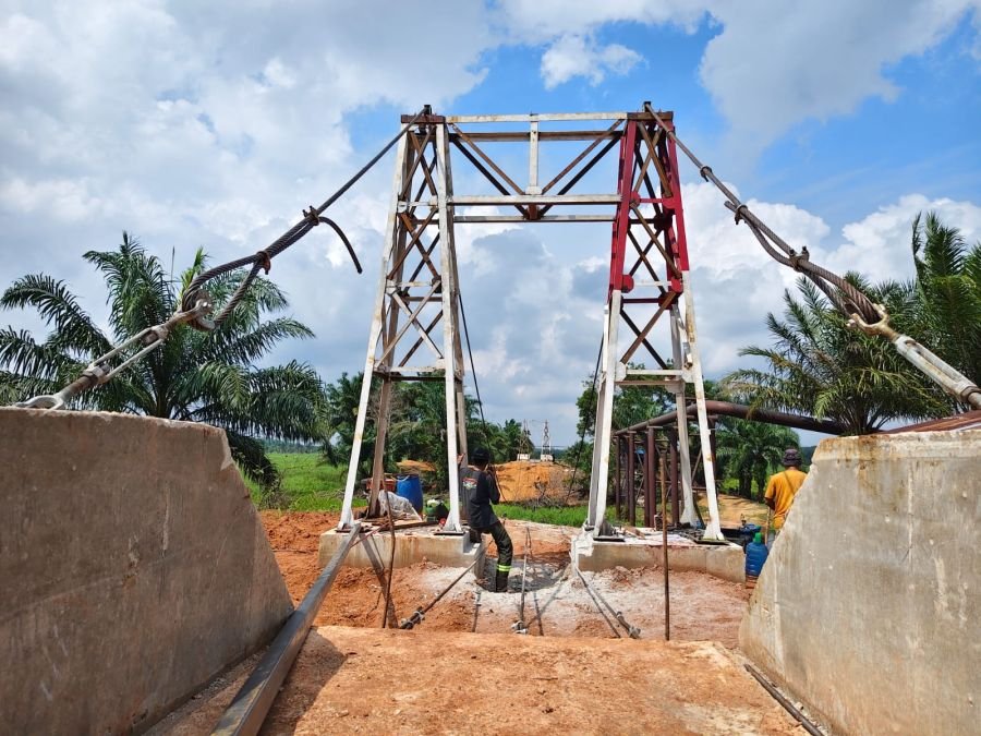 Kebut Pemasangan Tali Seling, Serka Irwanto Babinsa 05/Rimba Melintang Dampingi Pekerja Jembatan